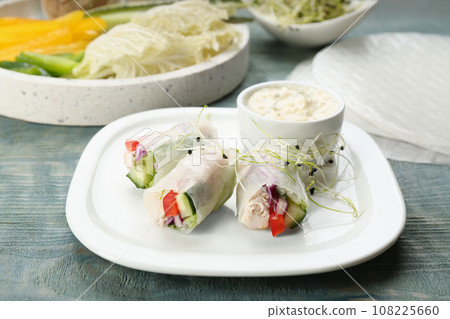 Delicious rolls wrapped in rice paper served on light blue wooden table Delicious rolls wrapped in rice paper served on light blue wooden table 108225660