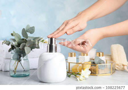 Woman using soap dispenser indoors, closeup view Woman using soap dispenser indoors, closeup view 108225677