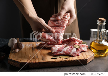 Man holding raw ribs at grey table, closeup 108225753