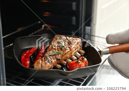 Chef taking delicious roasted ribs out of oven, closeup Chef taking delicious roasted ribs out of oven, closeup 108225794