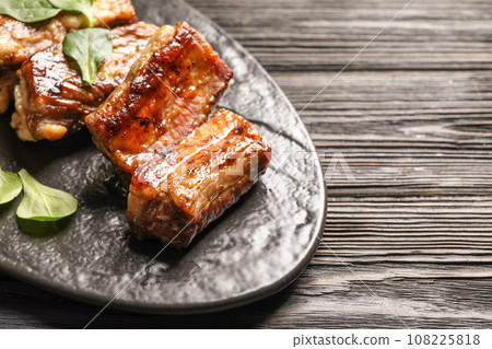 Delicious grilled ribs served on black wooden table, closeup. Space for text 108225818