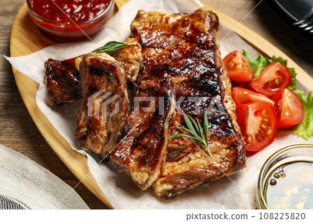 Delicious grilled ribs served on wooden table, closeup Delicious grilled ribs served on wooden table, closeup 108225820