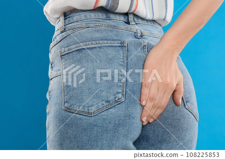 Woman suffering from hemorrhoid on light blue background, closeup Woman suffering from hemorrhoid on light blue background, closeup 108225853