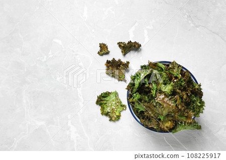 Tasty baked kale chips on grey marble table, flat lay. Space for text Tasty baked kale chips on grey marble table, flat lay. Space for text 108225917