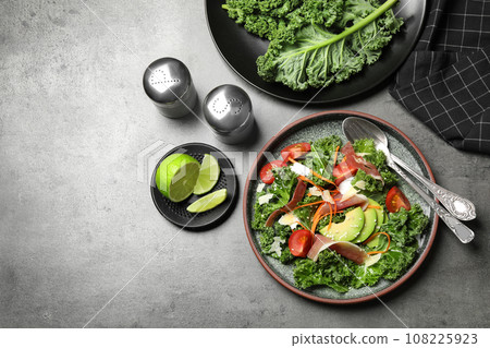 Delicious kale salad with prosciutto served on grey table, flat lay Delicious kale salad with prosciutto served on grey table, flat lay 108225923
