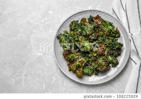 Tasty baked kale chips on light grey marble table, top view. Space for text Tasty baked kale chips on light grey marble table, top view. Space for text 108225929
