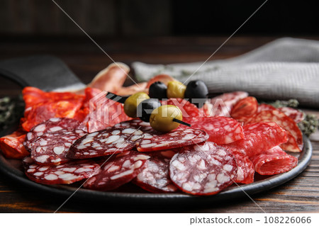 Tasty salami and other delicacies on wooden table, closeup 108226066
