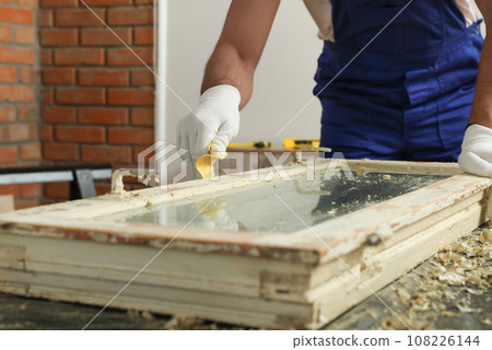 Man repairing old damaged window at table indoors, closeup 108226144
