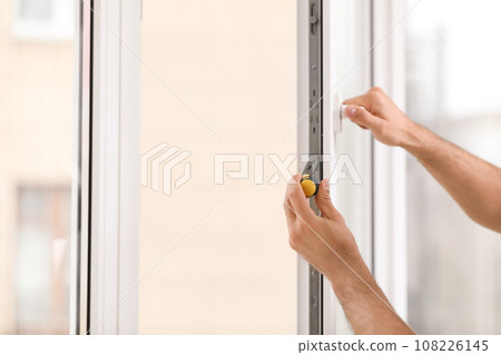 Construction worker repairing plastic window with screwdriver indoors, closeup Construction worker repairing plastic window with screwdriver indoors, closeup 108226145
