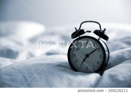 Alarm clock on bed, space for text. Morning time Alarm clock on bed, space for text. Morning time 108226211