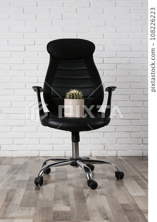 Office chair with cactus near white brick wall. Hemorrhoids concept 108226223