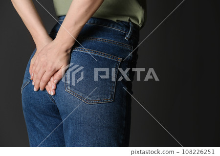 Woman suffering from hemorrhoid on black background, closeup. Space for text 108226251