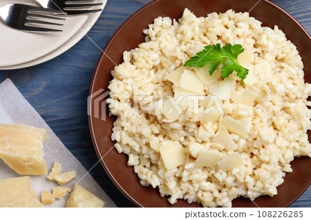 Delicious risotto with cheese on blue wooden table, flat lay Delicious risotto with cheese on blue wooden table, flat lay 108226285