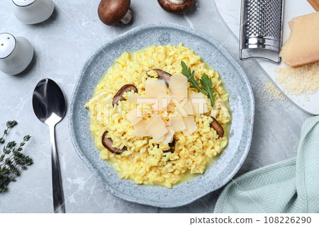 Delicious risotto with cheese and mushrooms on grey marble table, flat lay 108226290