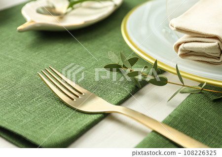 Stylish tableware with leaves on table. Festive setting Stylish tableware with leaves on table. Festive setting 108226325
