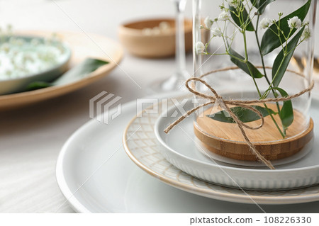 Glass with flowers on table, closeup. Festive setting Glass with flowers on table, closeup. Festive setting 108226330