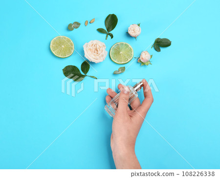 Top view of woman spraying perfume on blue background, flowers and lime representing aroma Top view of woman spraying perfume on blue background, flowers and lime representing aroma 108226338