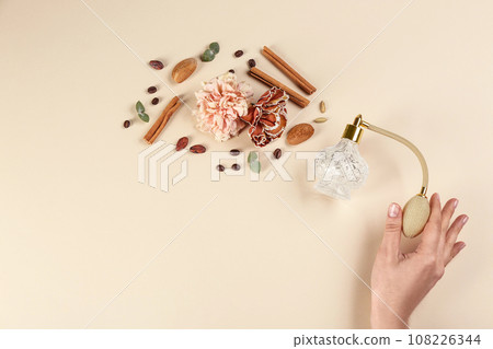 Woman with perfume. Fragrance composition, flowers and cinnamon on beige background,  top view 108226344