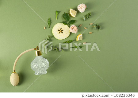 Flat lay composition with bottle of perfume on green background, space for text 108226346