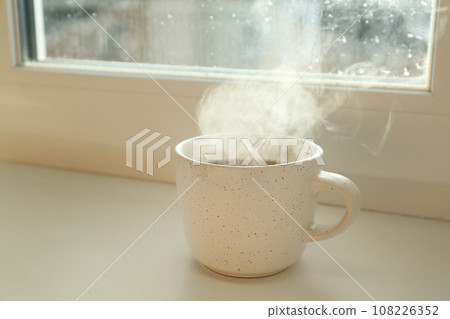 Cup of hot drink near window on rainy day Cup of hot drink near window on rainy day 108226352