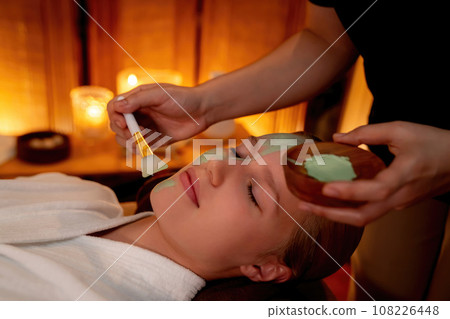 Woman indulges in rejuvenating with luxurious face cream spa massage. Quiescent Woman indulges in rejuvenating with luxurious face cream spa massage. Quiescent 108226448