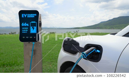 Electric car plugged in with charging station with nature background. Peruse 108226542