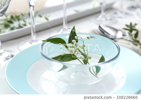 Stylish tableware with leaves and flowers on table, closeup. Festive setting 108226660