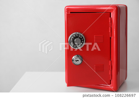 Red steel safe on white table against light background. Space for text Red steel safe on white table against light background. Space for text 108226697