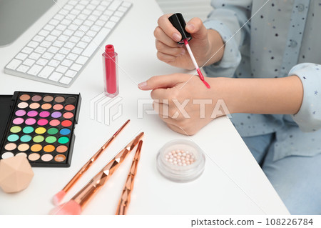 Beauty blogger doing lipgloss swatch at table, closeup Beauty blogger doing lipgloss swatch at table, closeup 108226784