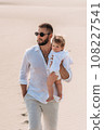 A stylish man with his baby in his arms. A small child in the arms of his father. A beautiful portrait of a child in the arms of his father. Family photo. Dad hugs the baby. 108227541