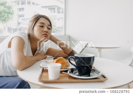 Sleepy and bored freelance woman working online in the cafe. 108228791