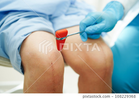 Asian doctor knock on knee reflex nerve for check and treatment senior patient in hospital. 108229368