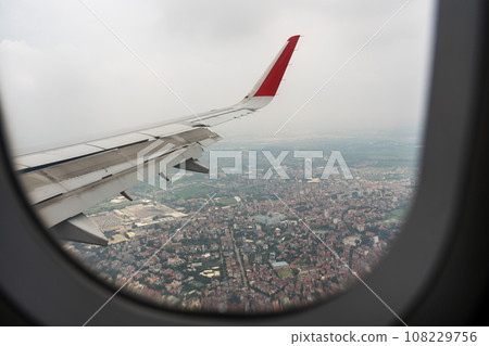 The wing of an airplane flying over Vietnam and the view below 108229756