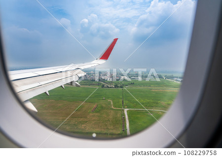 The wing of an airplane flying over Vietnam and the view below 108229758