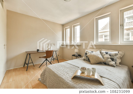 a bedroom with a bed, desk and window in the corners on the left side of the room is an open door 108231099