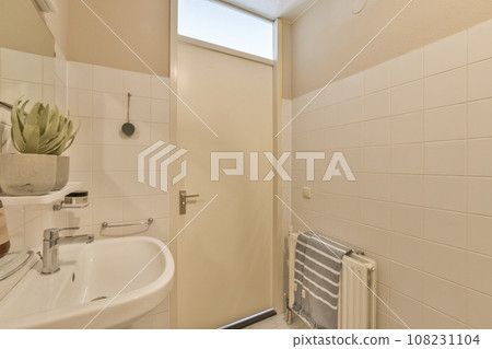 a bathroom with white tiles on the walls, and a toilet in the corner next to the sink is visible a bathroom with white tiles on the walls, and a toilet in the corner next to the sink is visible 108231104
