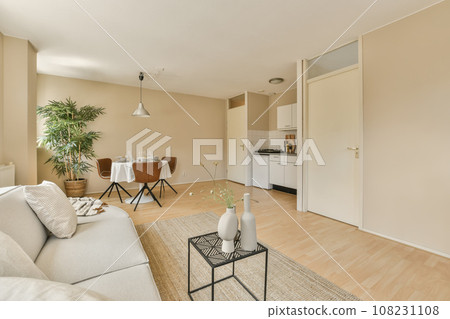 a living room with wood floors and beige walls, white furniture and an open door leading to the dining area 108231108