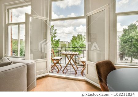 a living room with two windows and a table on the floor in front of the window looking out onto the street 108231824