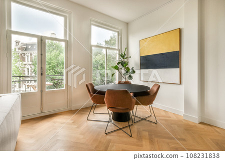 a living room with wood flooring and white walls, two large windows on the right side are lit by natural light a living room with wood flooring and white walls, two large windows on the right side are lit by natural light 108231838