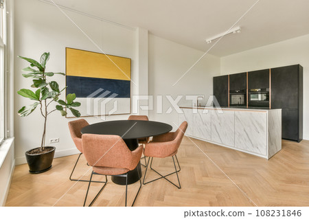a kitchen and dining area in a modern apartment with white walls, wood flooring and an orange chair next to the table 108231846
