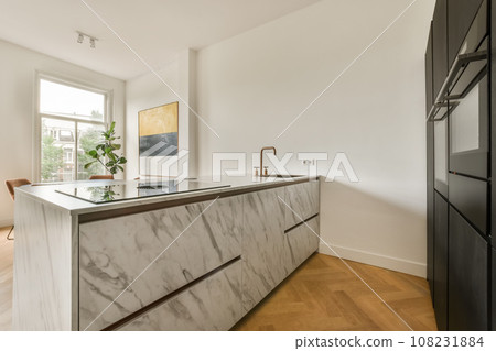 a modern kitchen with marble counter tops and black appliances in the room is white walls, hardwood flooring and wooden floors a modern kitchen with marble counter tops and black appliances in the room is white walls, hardwood flooring and wooden floors 108231884
