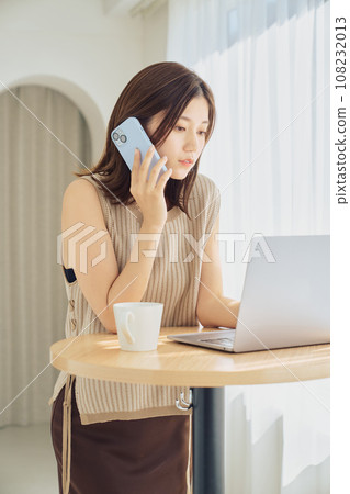 A woman working with a smartphone and computer 108232013
