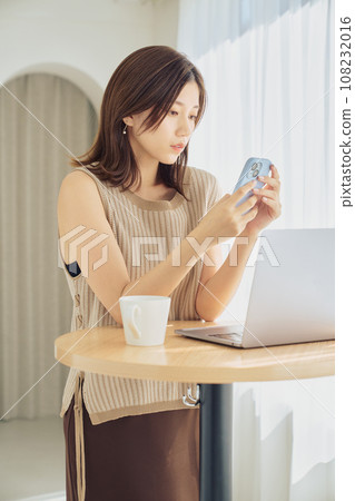A woman working with a smartphone and computer A woman working with a smartphone and computer 108232016