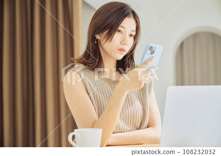 A woman working with a smartphone and computer A woman working with a smartphone and computer 108232032