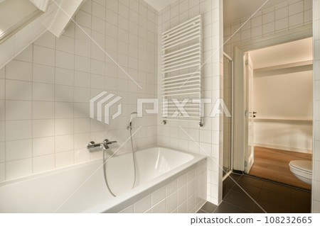 a bathroom with white tiles on the walls, and an open shower stall in the corner next to the bathtub a bathroom with white tiles on the walls, and an open shower stall in the corner next to the bathtub 108232665