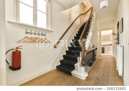 a staircase in a house with wood flooring and white trim on the stairs, there is a red fire exor 108232685