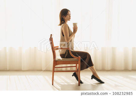 A woman drinking coffee at the window 108232985