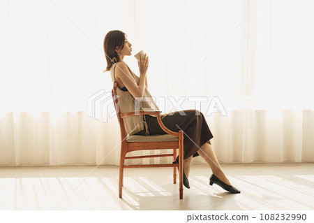 A woman drinking coffee at the window A woman drinking coffee at the window 108232990