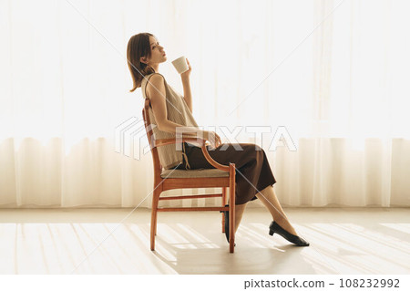 A woman drinking coffee at the window 108232992