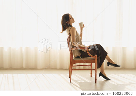 A woman drinking coffee at the window 108233003